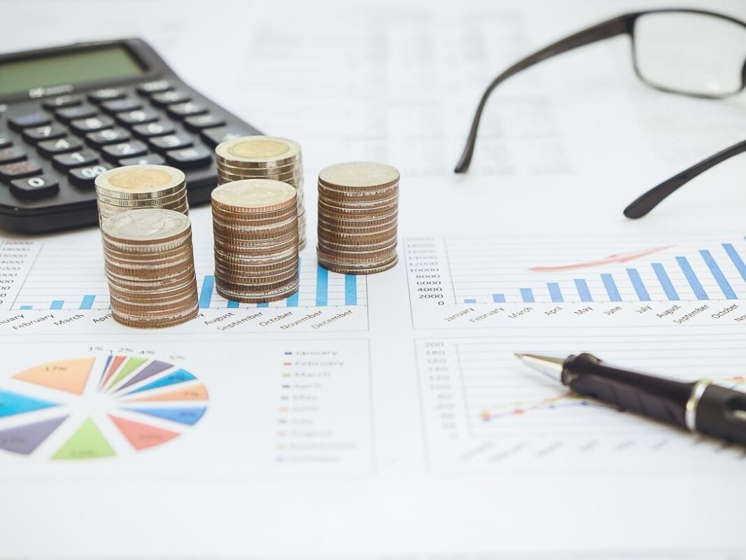 passer-en-societe Calculatrice, monnaie lunettes et stylo posés sur des graphiques pour l'analyse de passage en société