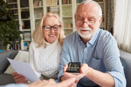 Femme pensionnée et homme pensionné qui calculent leur épargne pension avec une calculatrice