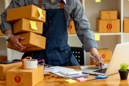 Buste d'un homme portant des boîtes en carton et occupé à rechercher des solutions de financement pour sa PME grâce au Tax Shelter